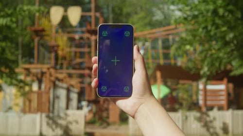 Young Woman Holding Phone Chroma Key Screen in Front of Playground Closeup Girl with Green Screen on