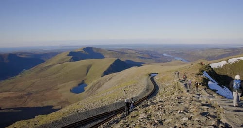 People hiking and climbing Snowdon mount in Wales on a sunny day