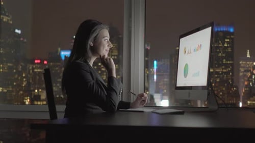 Young Confident Woman Working in Modern Office on Computer Desk At Night