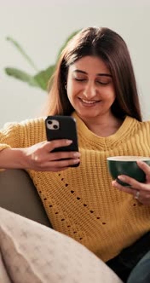 Smiling Woman Using Phone in Home with Hot Drink