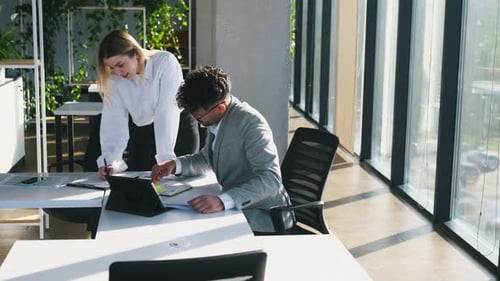 Working on a project together. Man and woman are indoors in modern building.