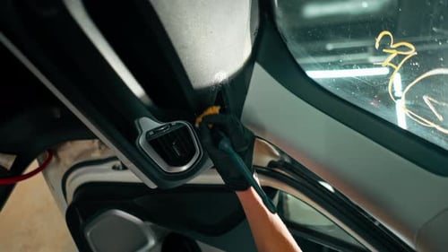 A close-up of a car wash worker using a brush and car chemicals to clean the dashboard of a car