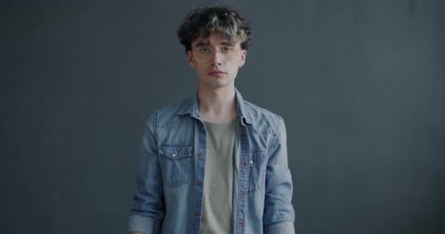 Portrait of Young Man Raising Crisis Banner Standing on Grey Color Studio Background and Looking at