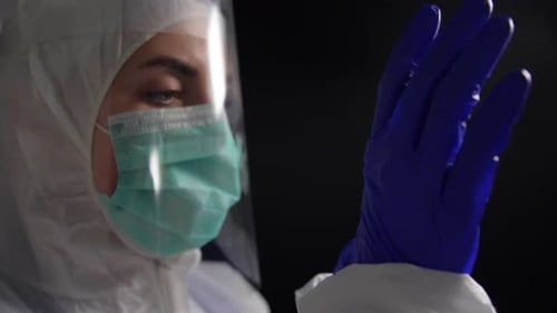 Healthcare Worker Putting on Gloves in Dark Room