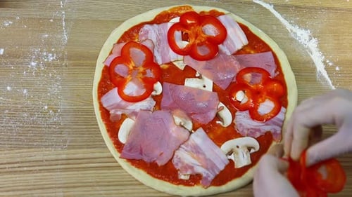 Making pizza in a restaurant. Cooking of pizza. Chef's hands spread pieces of tomatoes on pizza.