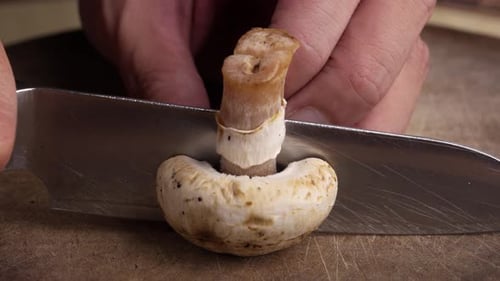 Tranchez un beau champignon de Paris blanc frais dans un gros plan culinaire lumineux