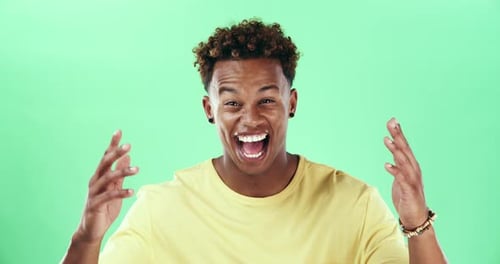 A young man looking surprised against a green studio background