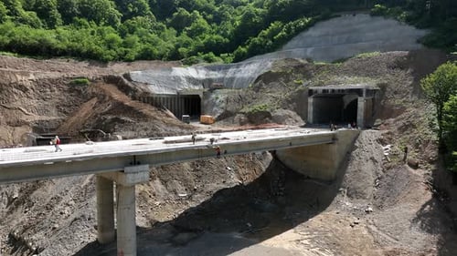 Aerial view of cranes and bridge foundation pillars on construction site of new highway road project