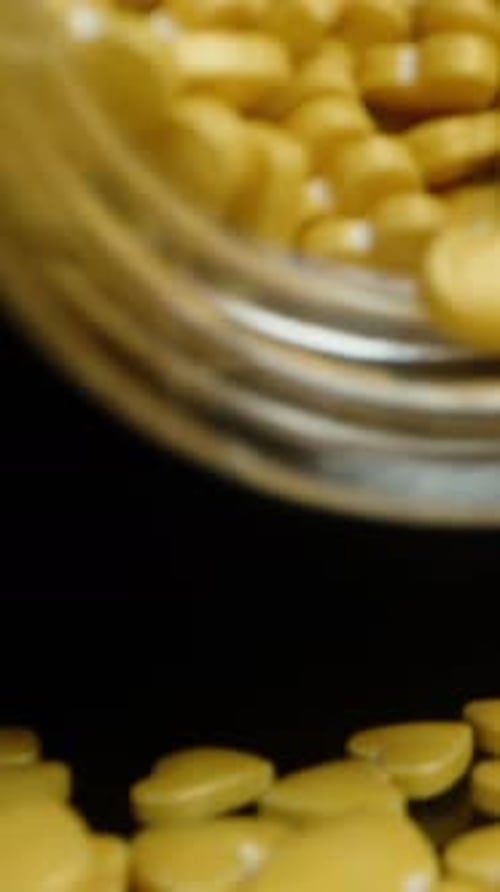 Yellow Heart Shaped Pills Falling From Jar