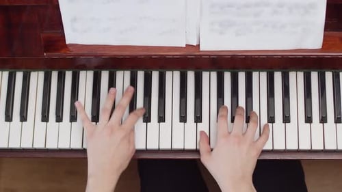 Musician playing the piano with his hands, top view. Artist plays chords according to notes on piano