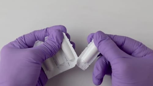 Gloved Hands Opening Medication Suppository Package