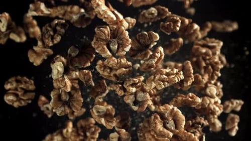 Shelled Walnuts Suspended in Air Against Black Background