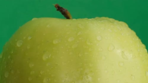 Grüner Apfel mit Wassertropfen auf grünem Hintergrund