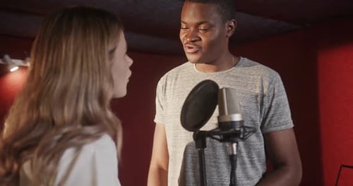 Multiracial Singers Performing Song Near Microphone in Studio