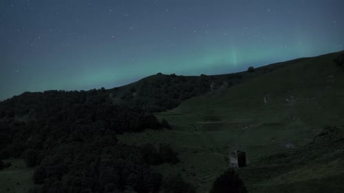 Northern Lights are shining over the green hill at night