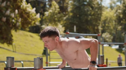 Athletic Caucasian Shirtless Man Practicing Dips on Parallel Bars Training Triceps on Playground