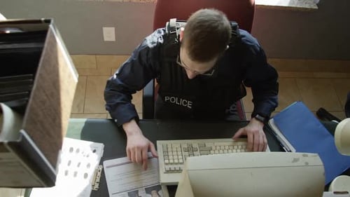 Police Officer Typing at Desk in Office