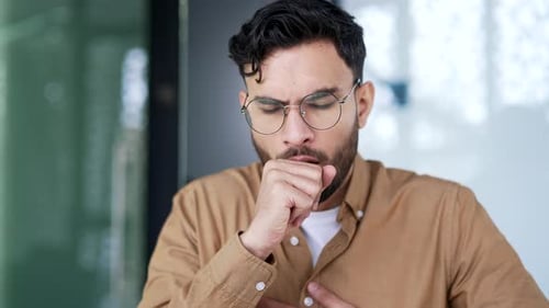 Unhealthy businessman coughing sitting at workplace in business office. Sick with cold or flu man
