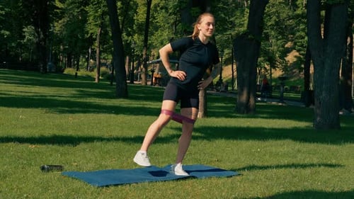Athletic Woman Exercising with Resistance Band in Park