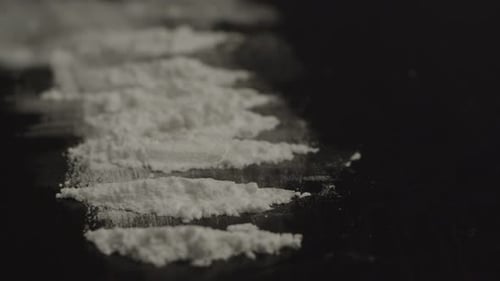 Extreme close of several lines of cocaine powder on black surface