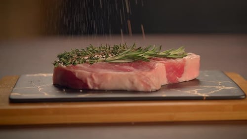 Seasoning Raw Steak with Rosemary and Thyme