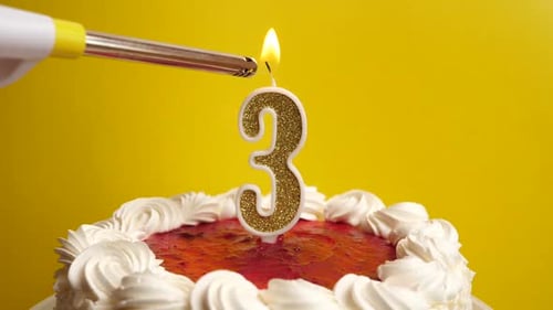 1. Se enciende una vela con la forma del número 3, insertada en el pastel navideño. Celebrando un nacimiento