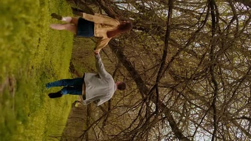 A young couple holding hands run through the forest, embodying an active lifestyle and tourism. Spor