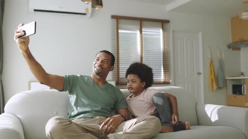 Father and Child Taking Selfie on Couch