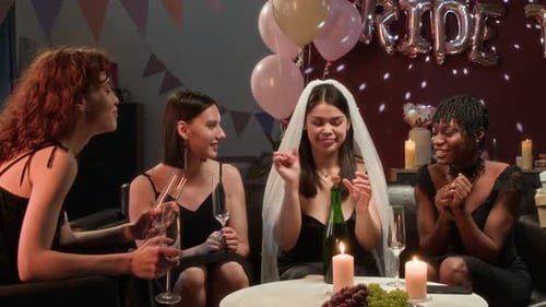 Happy Bride Pouring Champagne for Friends during Bachelorette Party