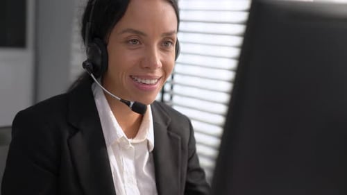 Kompetente Bedienerin, die am Computer arbeitet und mit Kunden spricht