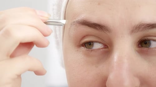 Close-up of Woman Tweezing Eyebrows