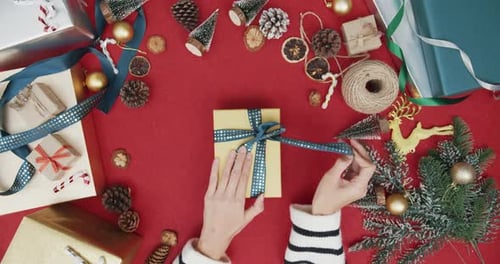 Top view of girl hands unpacking present gift box winter christmas decorations on red background.