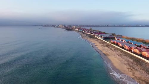 Aerial View of the Shore with Grass and Houses Surrounded By the Black Sea Under a Clear Sky in