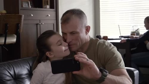 Father and daughter taking selfie together at home