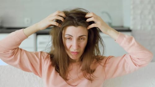 Photo of a Frustrated Young Woman with Brown Hair Scratching Her Head Due to a Persistent Itch