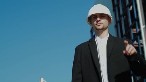 Engineer in Hardhat Gesturing Toward the Sky