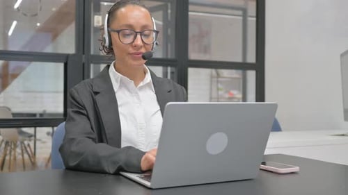 Woman with Headset Working on Laptop in Office