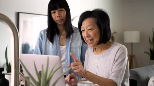 Daughter Helping Senior Mother Using Laptop At Home