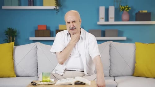 Senior Man Sitting on Sofa with Sore Throat