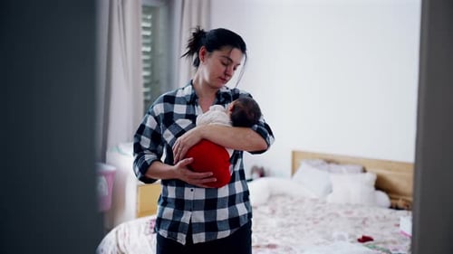 Loving Woman Holding a Newborn Baby Indoors