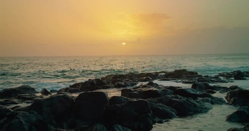 Calming seascape during sunset. Close-up rocky beach glistening ocean water at dusk sky. Sea backgro