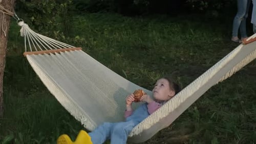 Cute Girl Eating Pastry in Outdoor Hammock