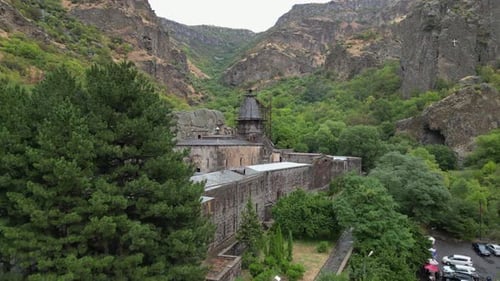 Aerial rises over Geghard Monastery in rugged Armenian rock gorge
