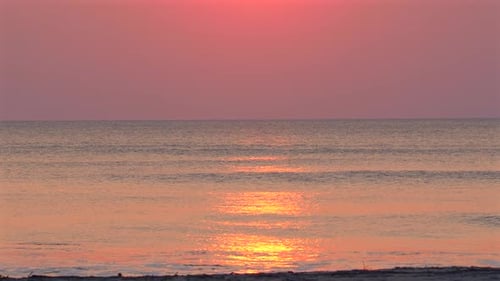 Tranquil Sunrise Over Calm Sea with Reflections and Warm Hues