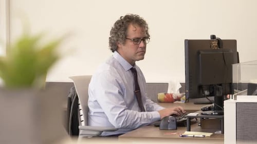Homme d'affaires mature tapant sur ordinateur au poste de travail dans un bureau moderne
