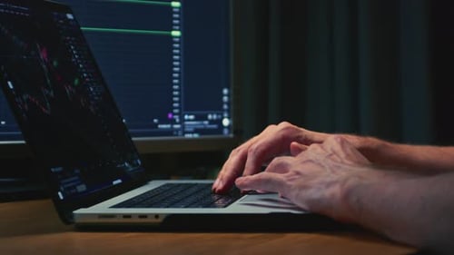 Man Stock Trader in Home Office Typing on a Laptop Keyboard Male Analyzes Terminal Trades Stocks on