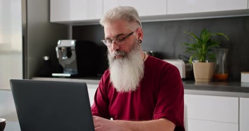 Senior Man Working on Laptop in Modern Kitchen