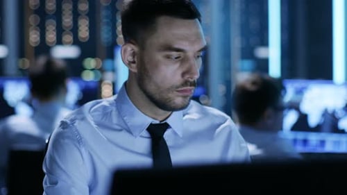 Primer plano de un controlador técnico profesional sentado en su escritorio con varias pantallas ante H