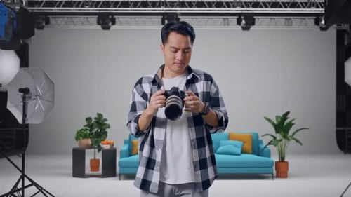 Asian Photographer Changing Lens Of Camera Before Using It Taking Pictures In The Studio