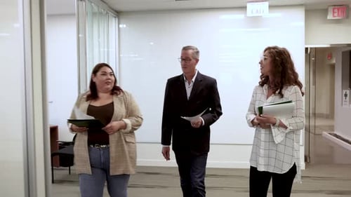 Team Members Walking Through Office Discussing Documents